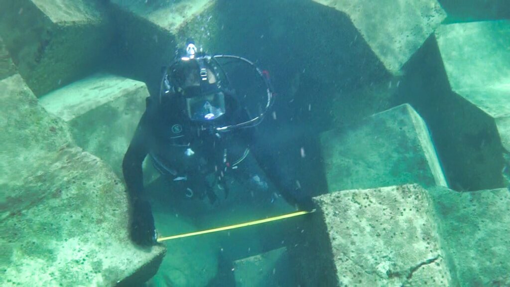 Plongeur inspectant sous l’eau les non-conformités d’imbrication des blocs de carapace sur l’île de Das Island afin de garantir la stabilité et la durabilité de l’ouvrage.