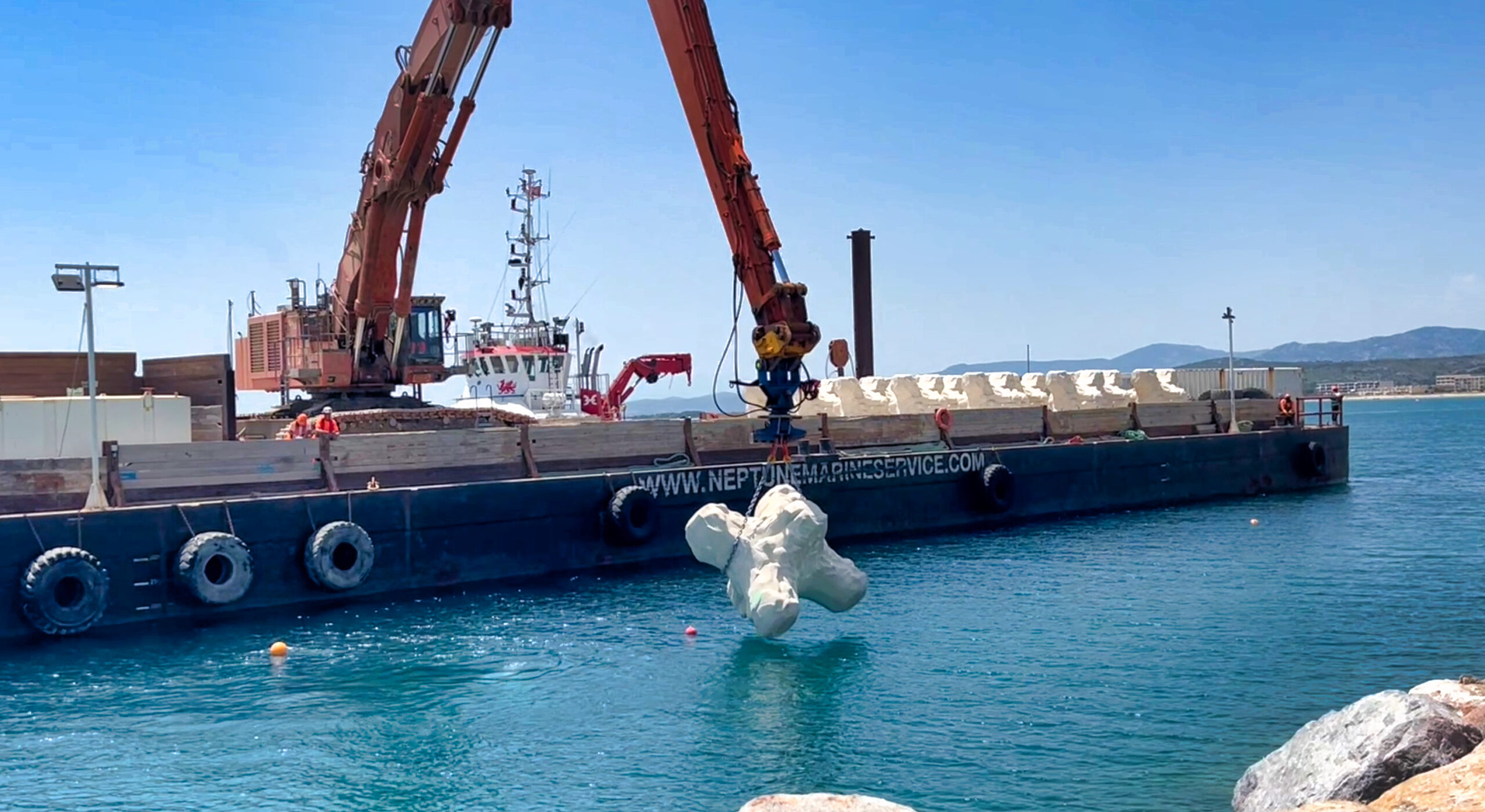 Pose de blocs artificiels sur un brise-lames depuis une barge