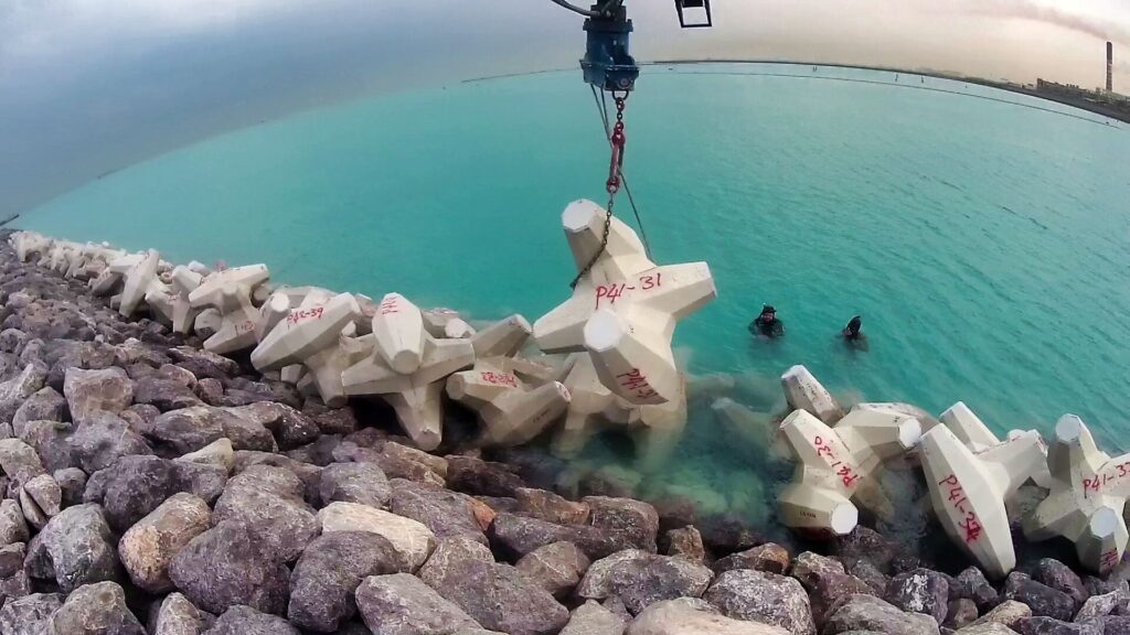 CLAS inspector training divers on the Al Zour construction site in Kuwait, demonstrating the safe removal of a broken CORELOC™ armour unit through hands-on supervision.