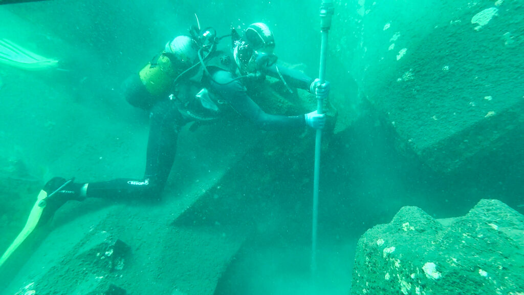 Sondage à la lance réalisé par un expert CLAS pour mesurer l’épaisseur de la sous-couche sableuse sous une carapace en blocs artificiels sans démontage