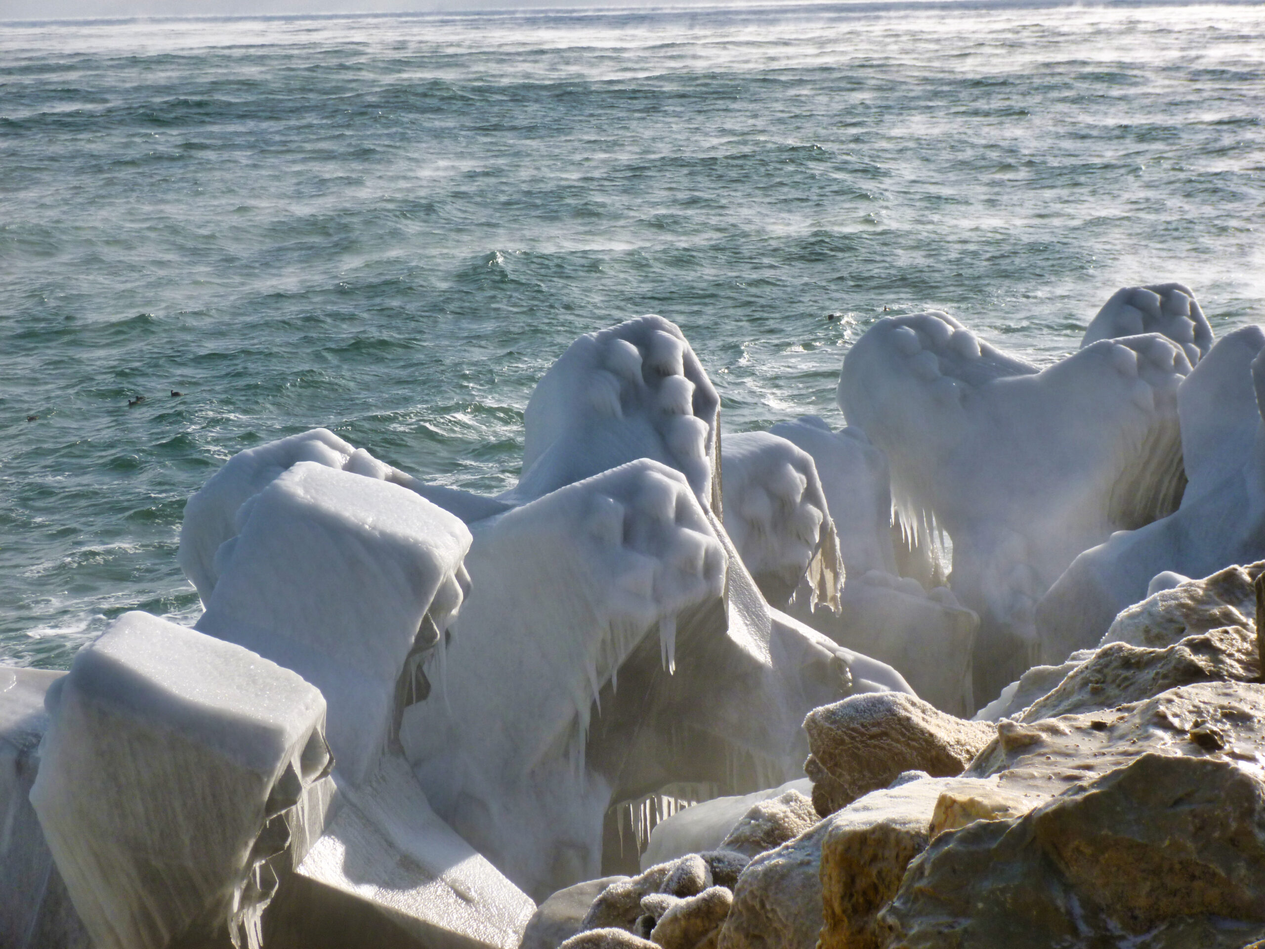 Blocs de carapace recouverts de glace pendant l’hiver, montrant les conditions extrêmes auxquelles la digue est exposée.