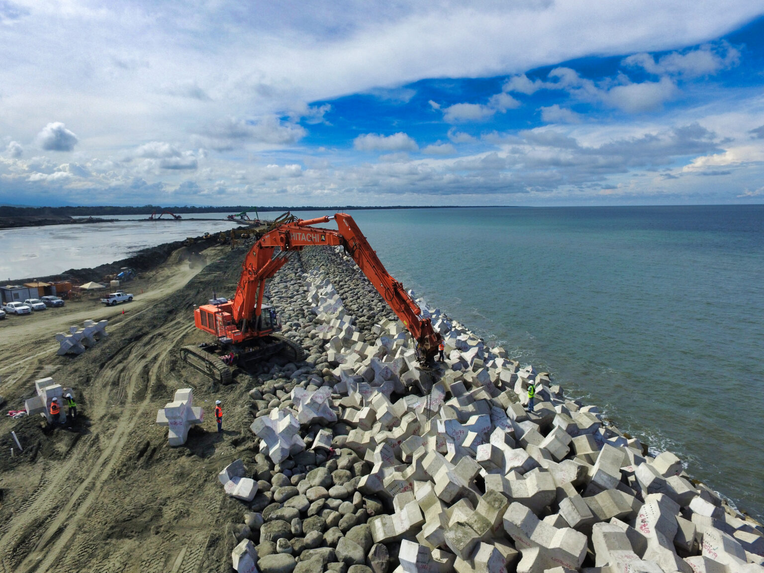 Pose de blocs artificiels sur la crête de la digue pour assurer l’imbrication et la stabilité de la carapace.