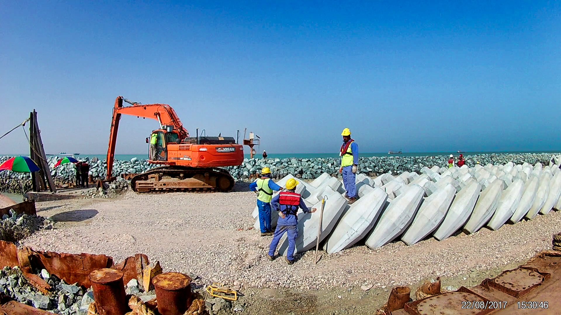 Barge with crane placing armour units on the Al Faw breakwater construction site in Iraq