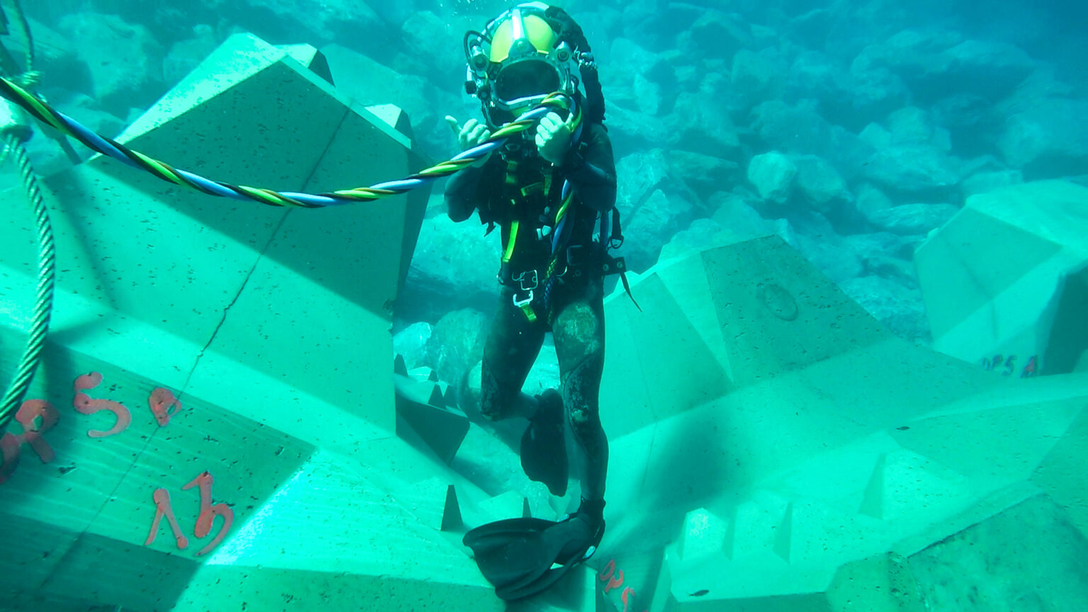 Plongeur en action posant un bloc de carapace sous la supervision des experts CLAS sur la digue de Bastia