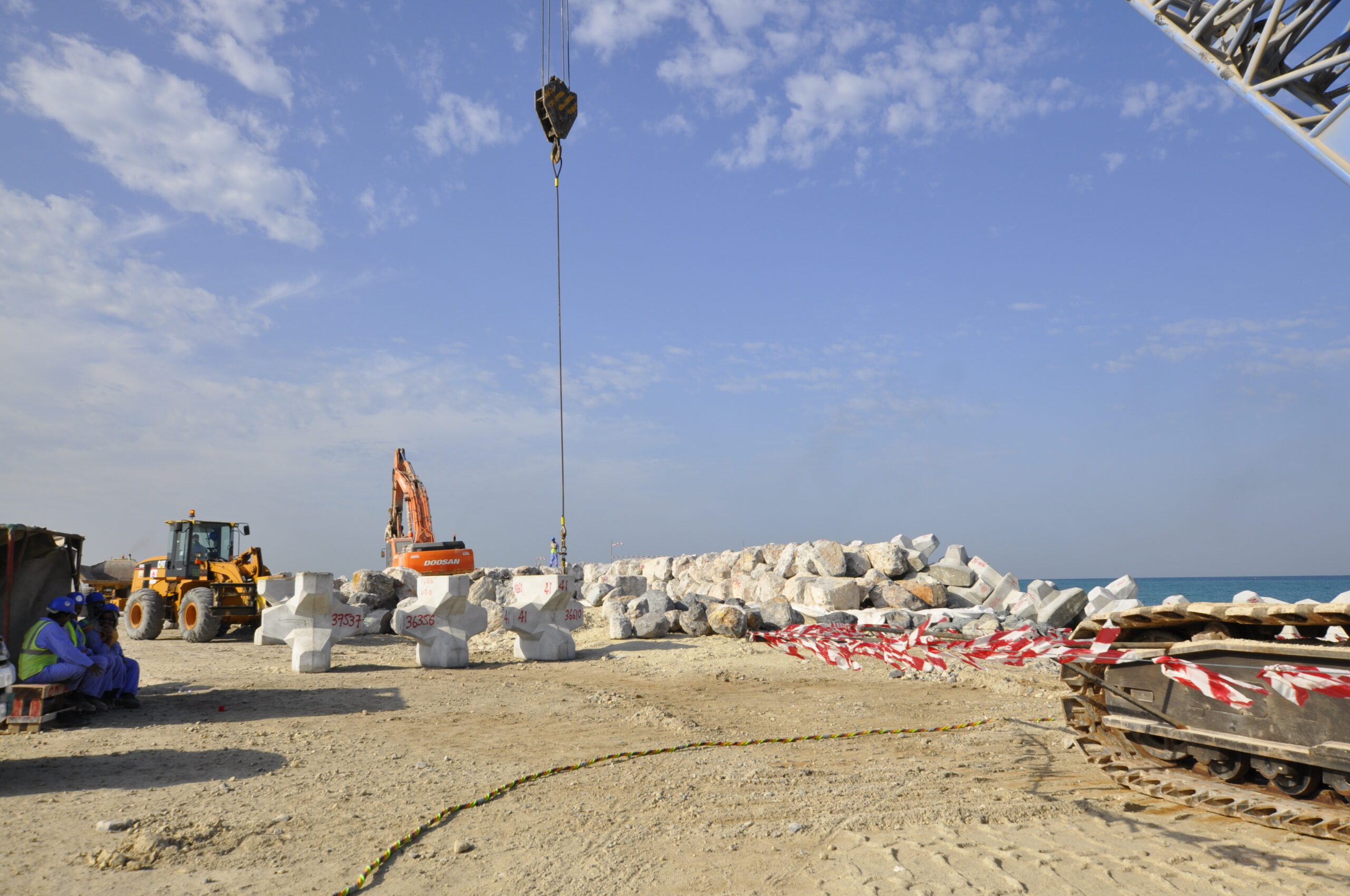Pose des blocs de carapace sur le chantier, réalisée sous la supervision des experts CLAS pour garantir une imbrication précise et conforme aux tolérances.