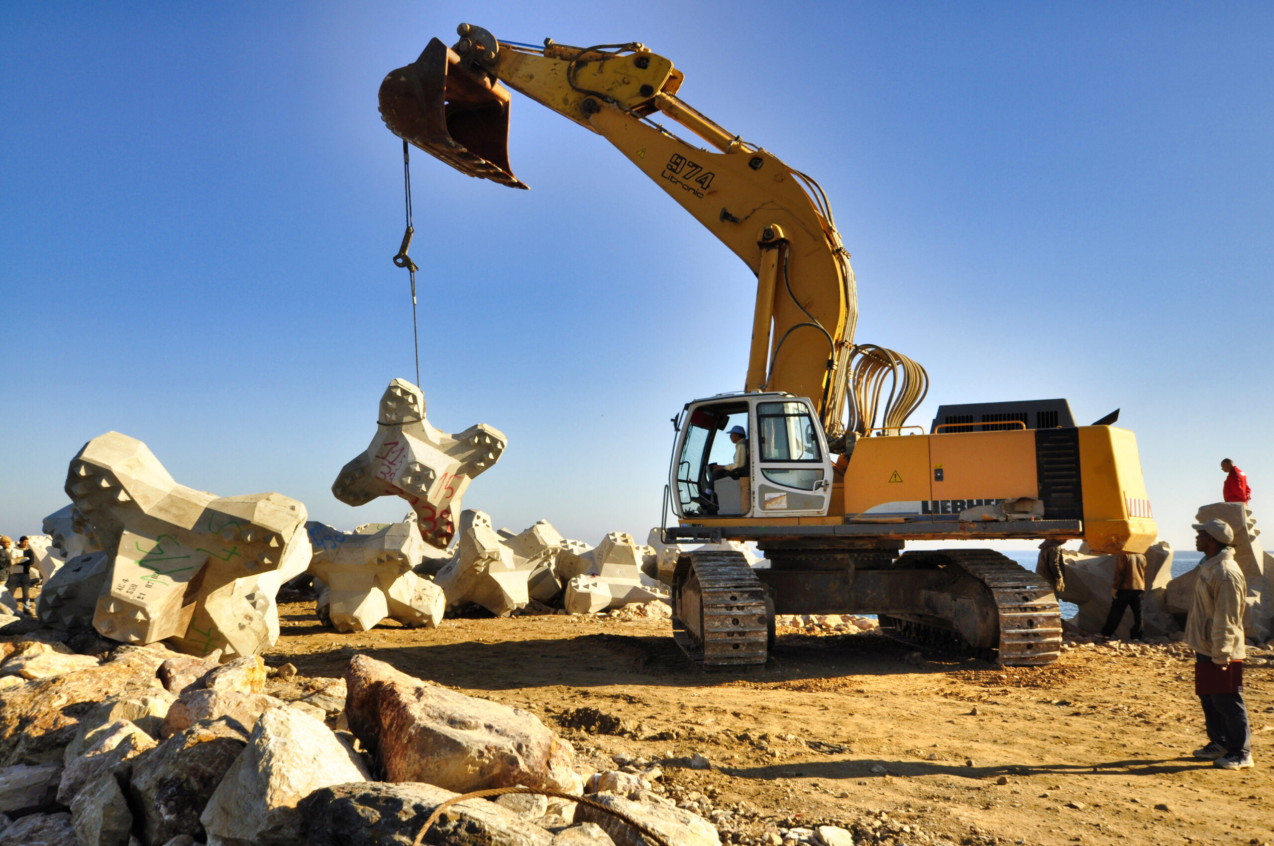 Travail de construction de la digue montrant la mise en place des blocs et le contrôle qualité réalisé par CLAS.