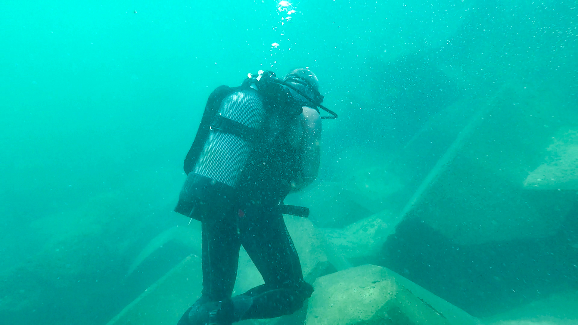 Plongeur CLAS inspectant sous l’eau la carapace d’une digue pour vérifier l’imbrication et la stabilité des blocs.