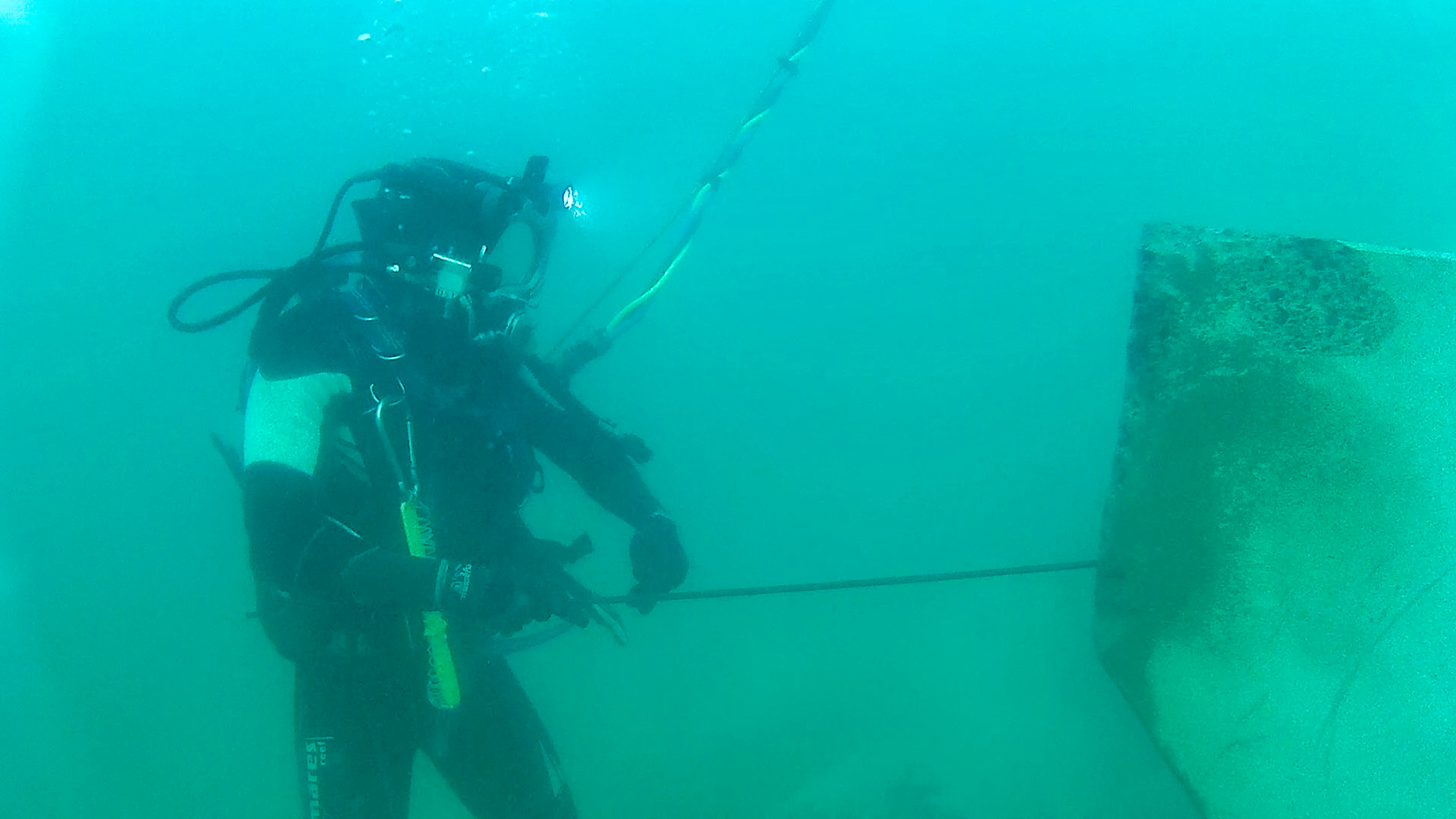 Plongeur ajustant la pose des blocs artificiels sous l’eau et guidant le grutier pour garantir une imbrication précise.