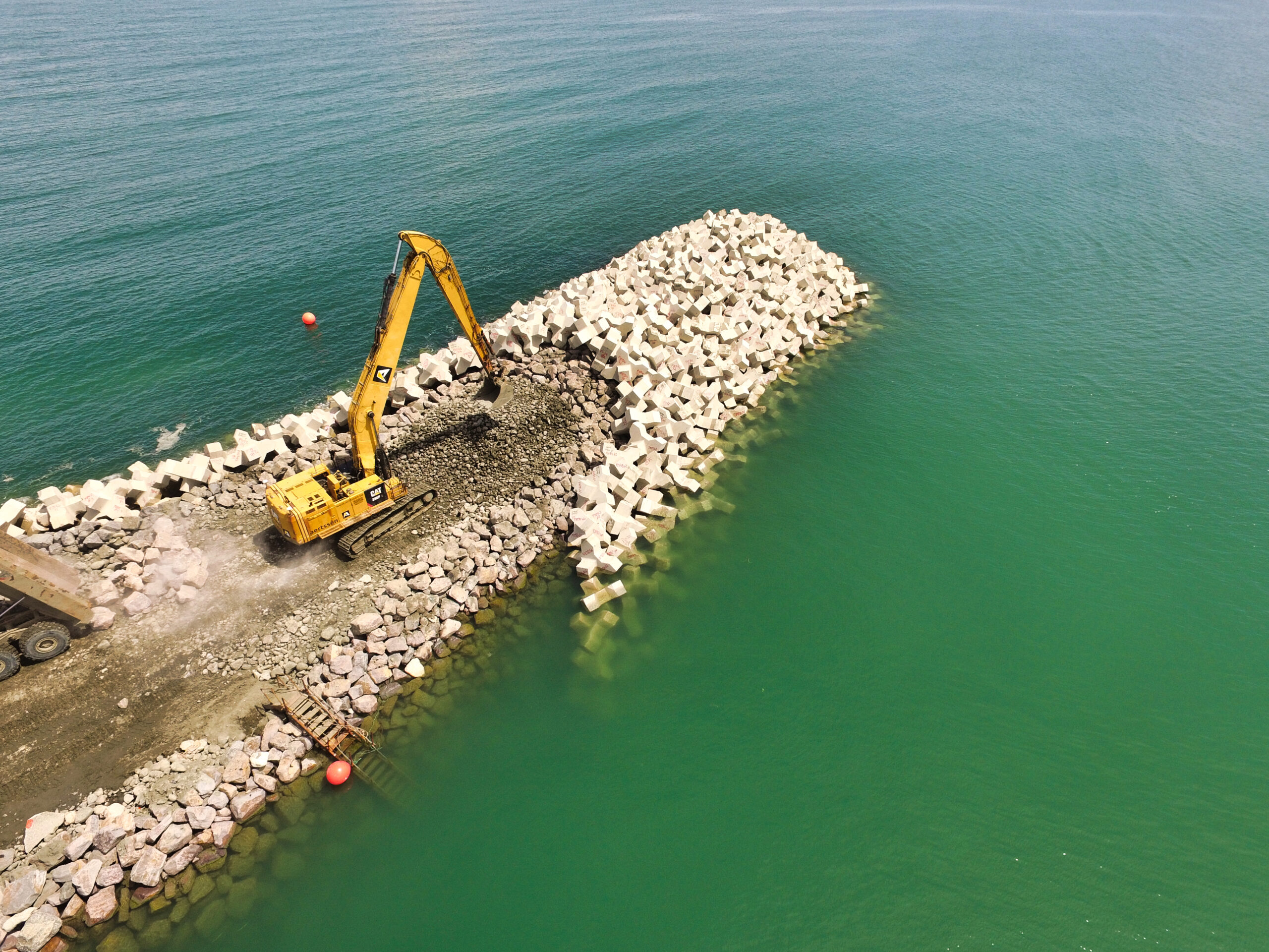 Vue drone montrant la construction du musoir de la digue avec des blocs artificiels.