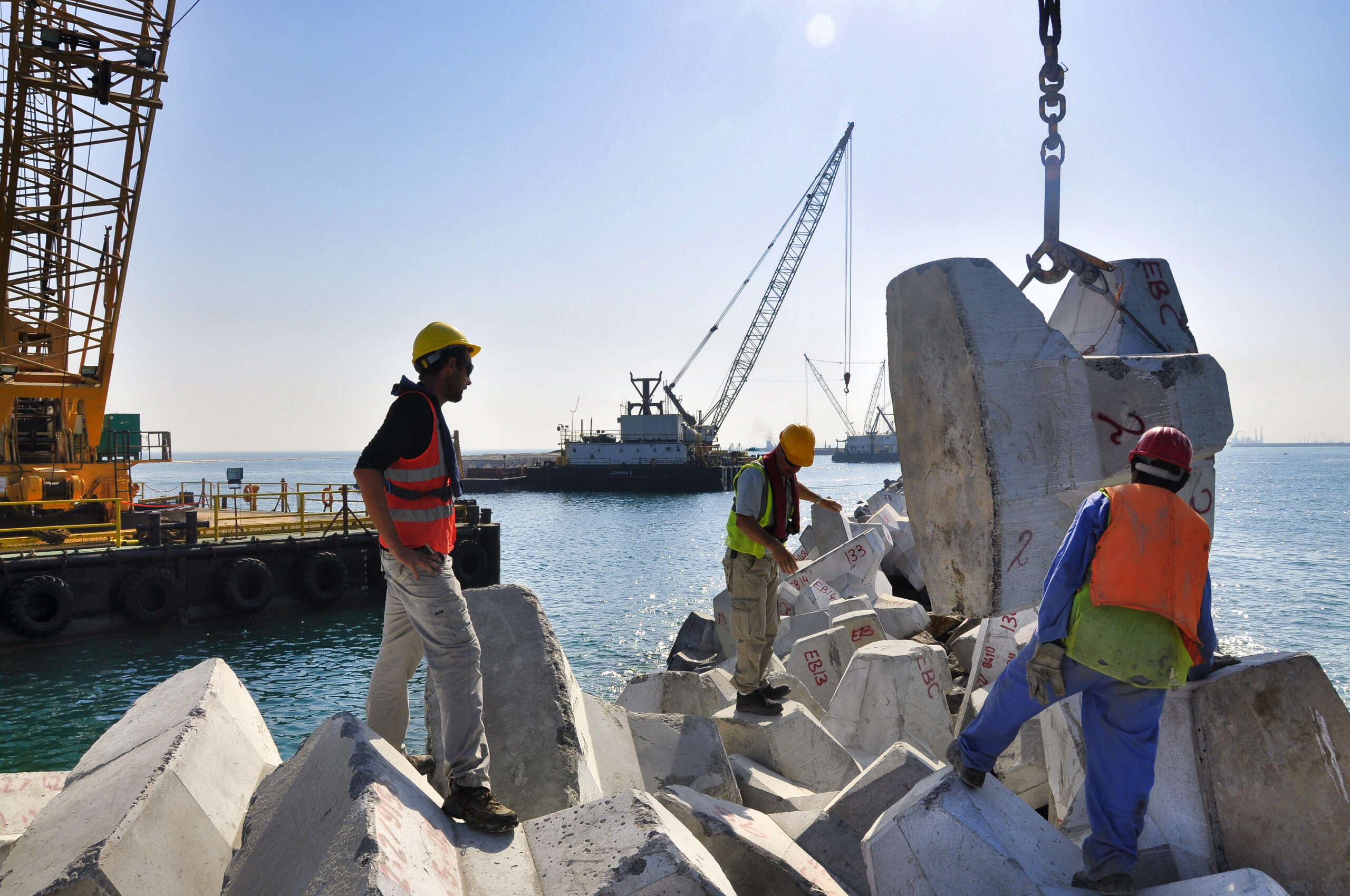 Expert CLAS contrôlant l’ajustement d’un bloc en crête de digue étroite pour garantir une imbrication correcte et une stabilité optimale.