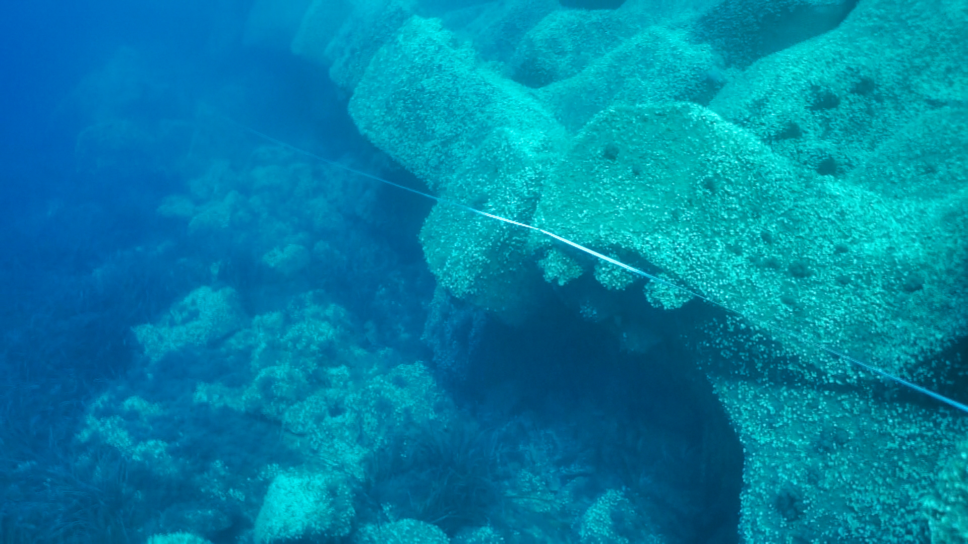 Vue sous-marine montrant l’absence de butée de pied devant la carapace en blocs artificiels, exposant la digue à des risques d’affouillement.