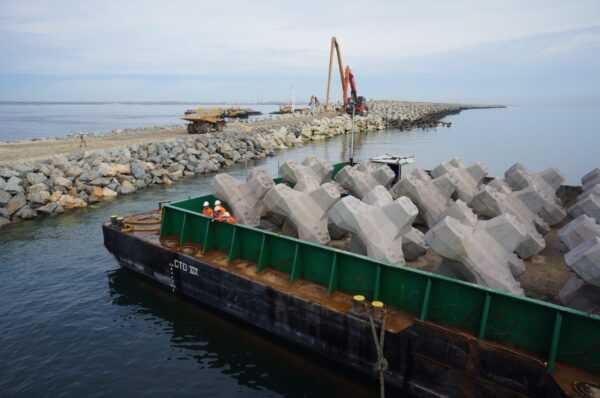 Blocs artificiels en béton stockés sur une barge avant leur mise en place sur une digue portuaire
